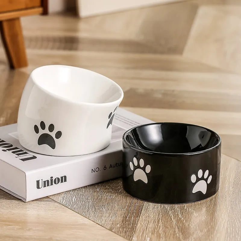 Ceramic cat food bowl with high foot base in a cat's paw print design