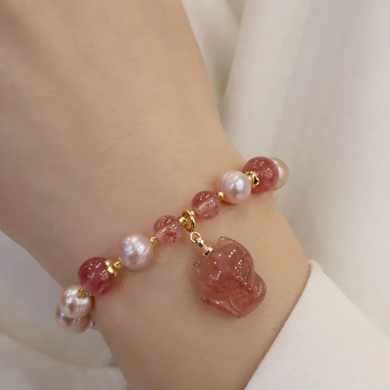 Women's light pink freshwater pearl bracelet with strawberry quartz and fox charm on wrist
