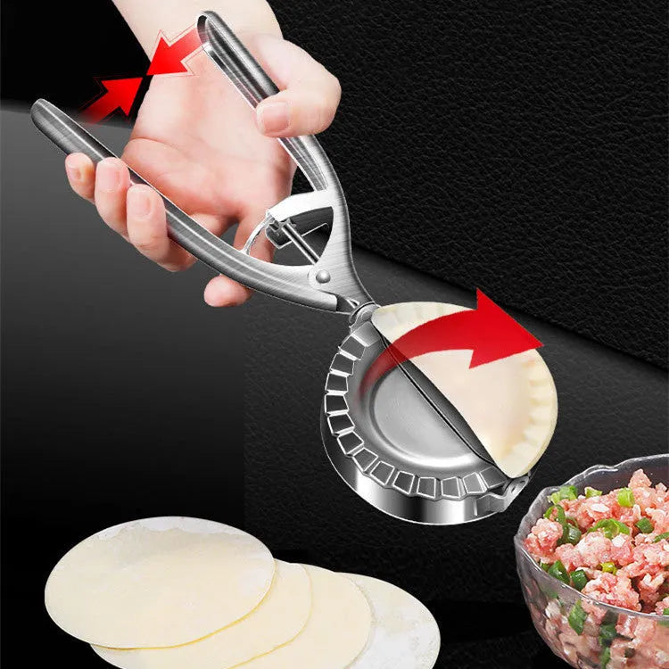 Silver stainless steel manual dumpling maker press tool on a kitchen surface.