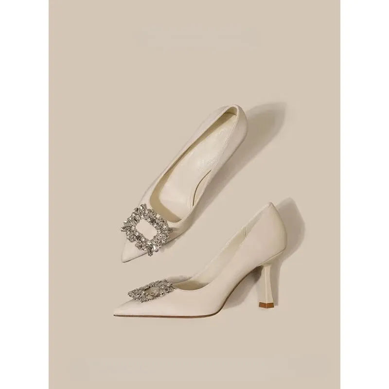 Women's creamy-white pointed toe stiletto high heels with a mid-height heel on a plain background.