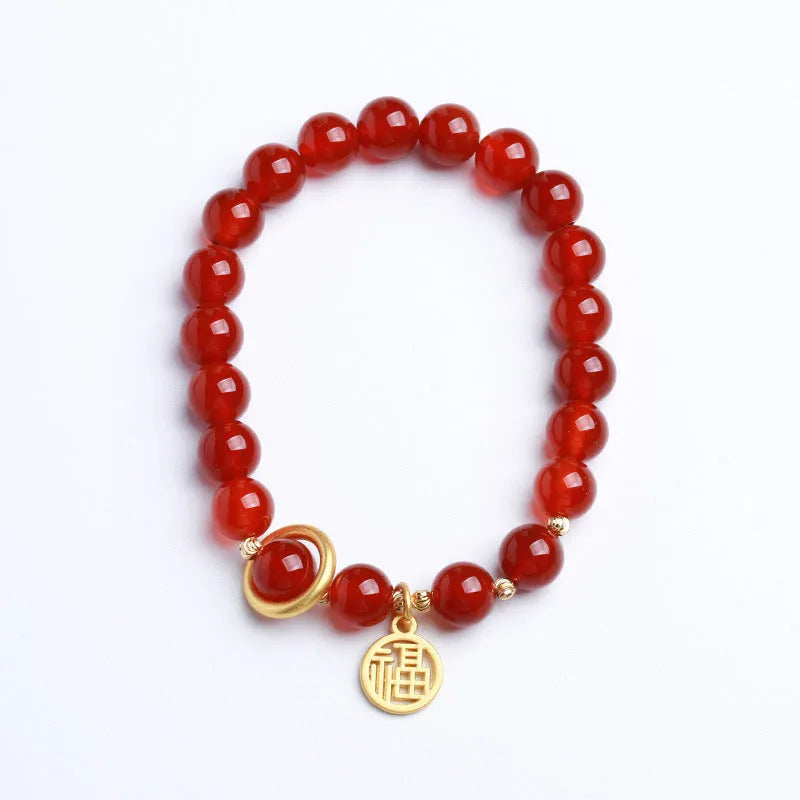 Close-up of a red agate beaded bracelet with woven design and a paper blessing card.
