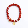 Close-up of a red agate beaded bracelet with woven design and a paper blessing card.