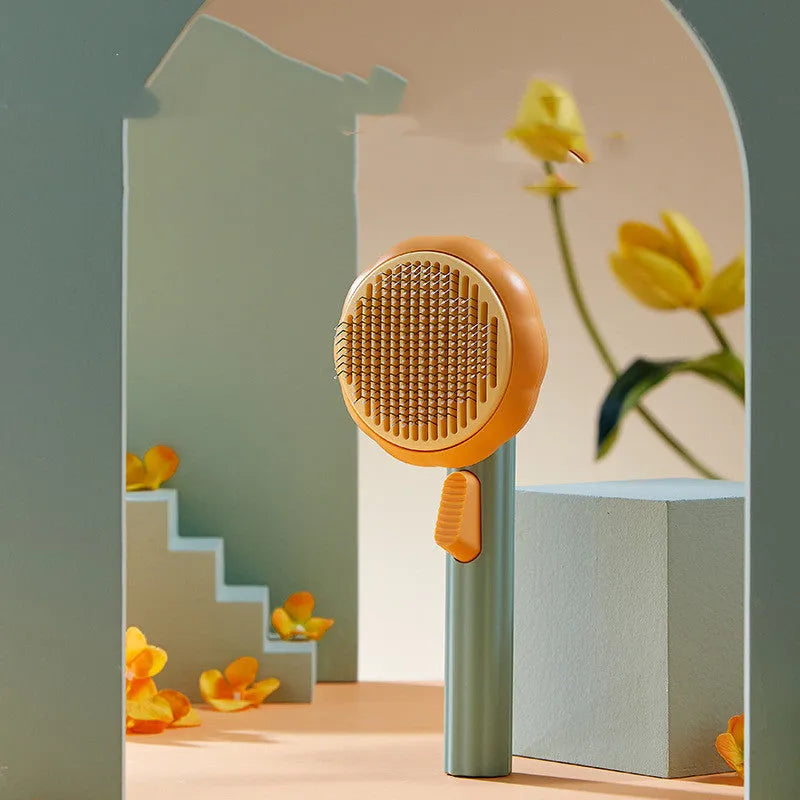 Pumpkin-coloured hand-held pet brush with curved stainless steel teeth for grooming cats and dogs