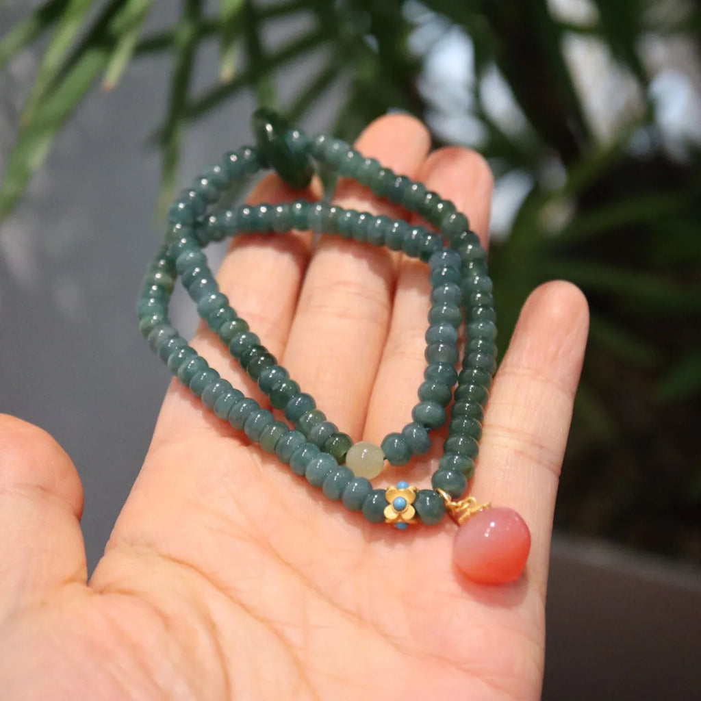 Women's bracelet with small blue water jade abacus beads, tourmaline rings, and pearls on a wrist