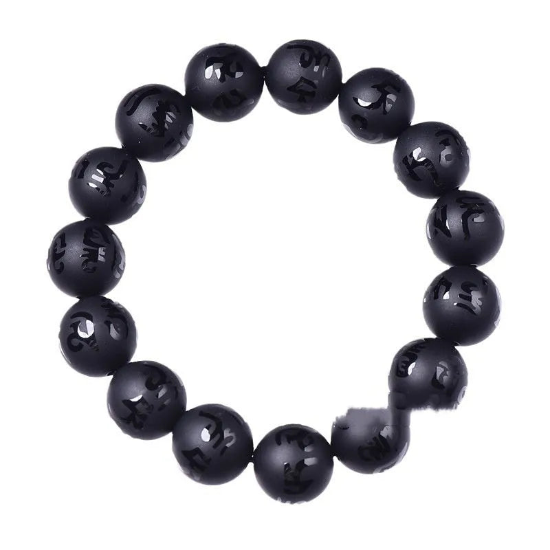 Close-up of a frosted black agate bracelet with Sanskrit mantra engraving on each bead, showing matte stone texture.