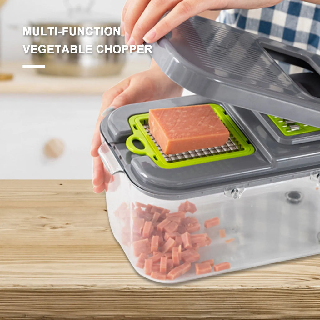 Grey multifunctional vegetable cutter with stainless steel blades, foldable compartments, and water filter basket on a kitchen countertop.