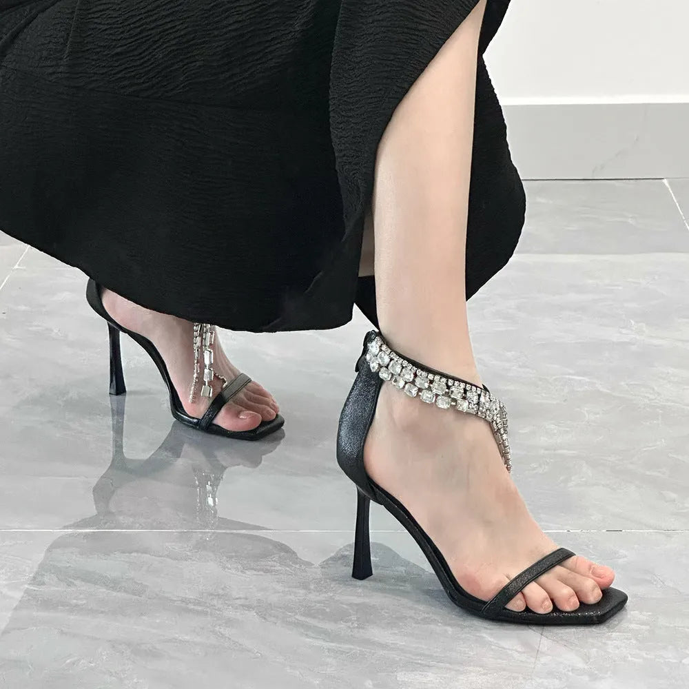 Women's black high heel sandals with 8cm heel, ankle strap buckle, and square open toe on a plain background.