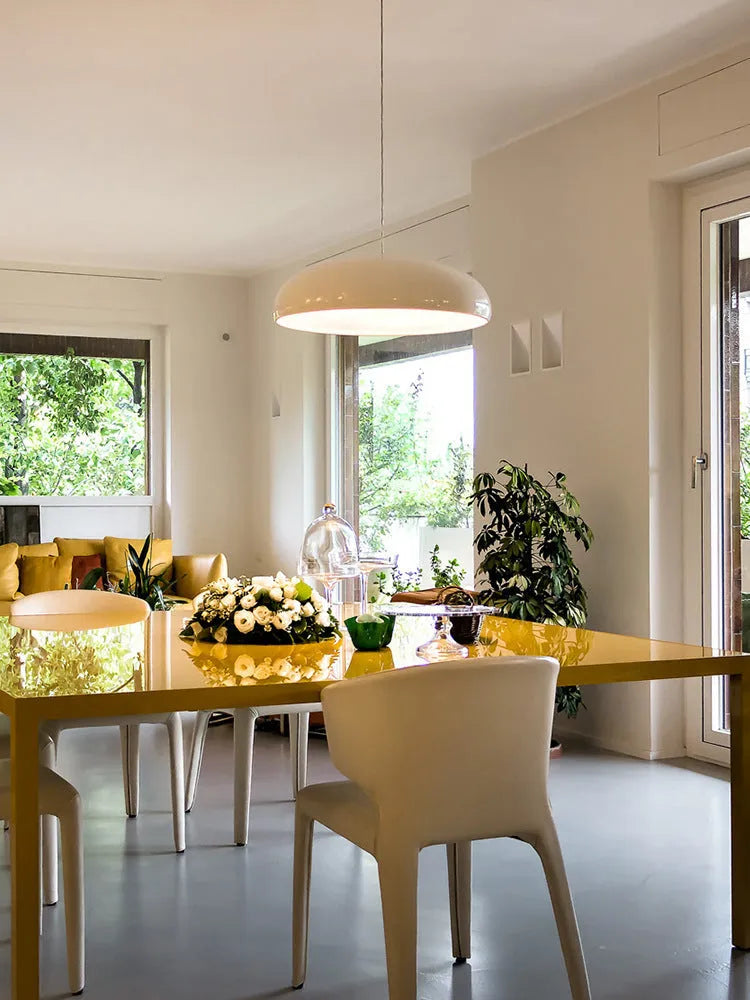 Orange iron Danish-style pendant lamp with adjustable cable above a restaurant table.