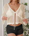 Short apricot coloured women's cardigan blouse with flared bell sleeves, laid flat.