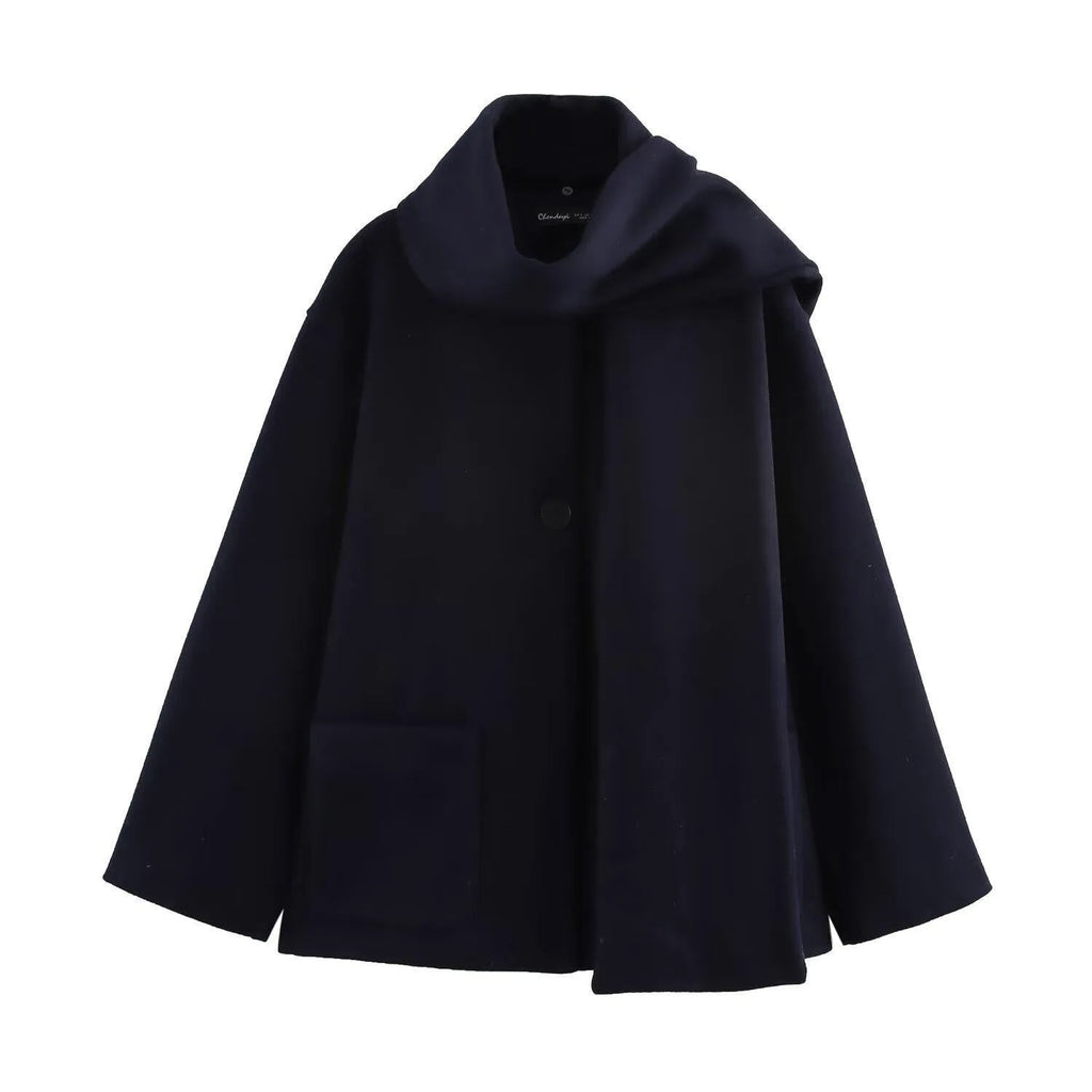 Women's long black coat with a grey artificial fur collar and side pockets, shown in a street fashion setting.