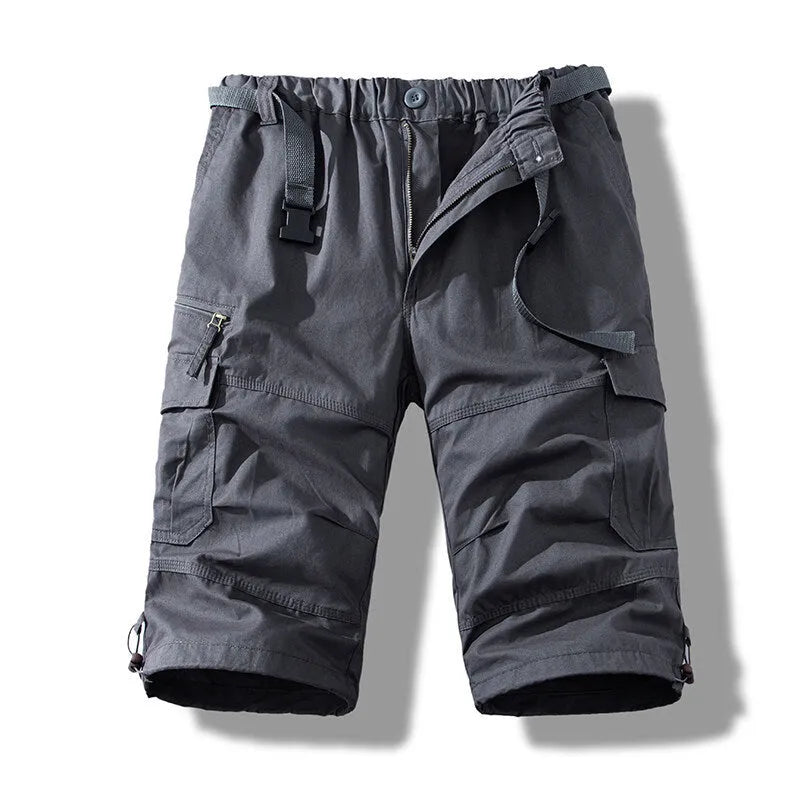 Men's cotton cropped overalls in army green, shown in a casual summer setting.