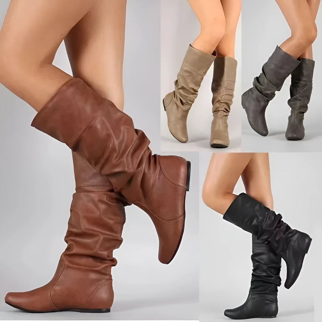 Women's black flat slip-on ankle boots with round toe and high cylinder cut, showing rubber sole.