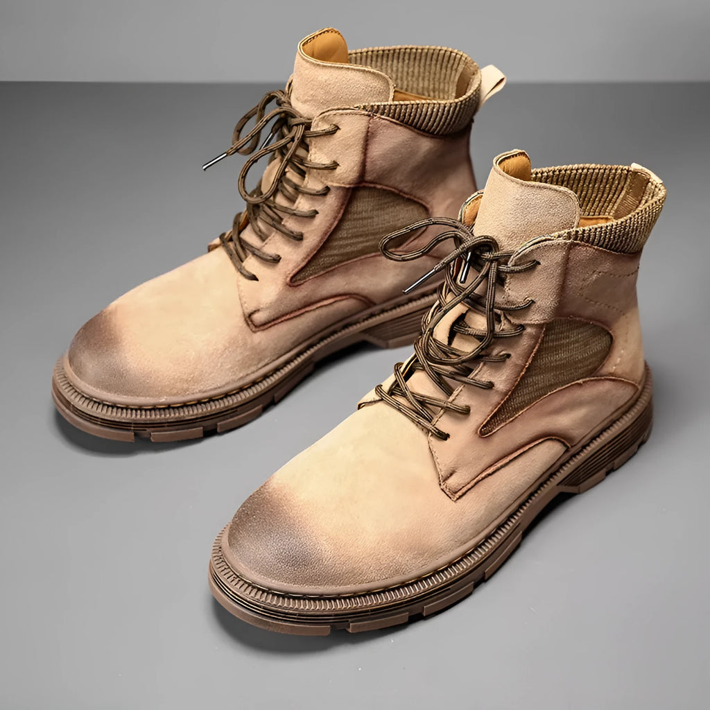 Men's ankle-high Martin boots in frosted grey leather with a thick rubber sole and round toe on a wooden floor.