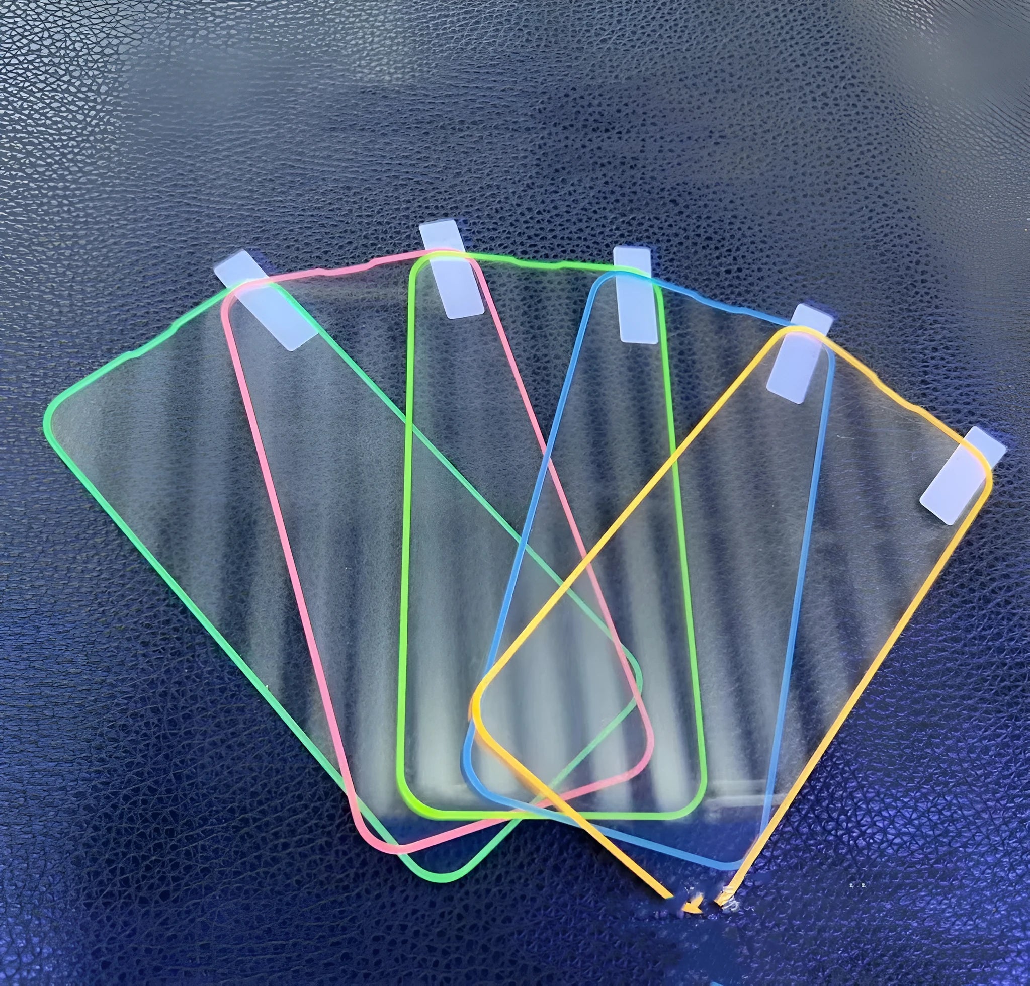 Fluorescent tempered glass screen protector glowing on an iPhone 13, showing pink luminous edge and precise camera cutout.