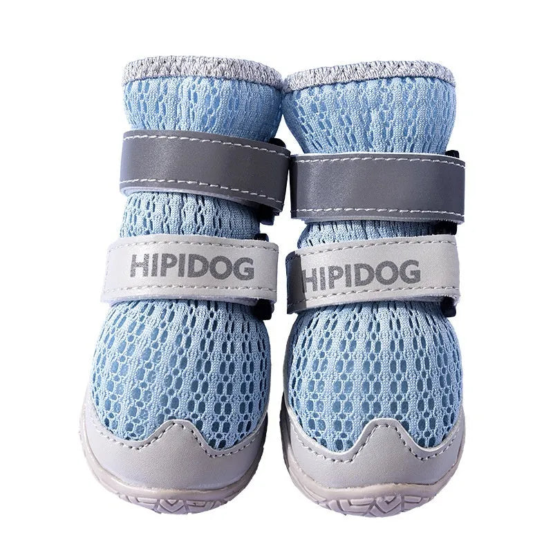 Pair of blue and green breathable mesh dog shoes with thick rubber soles and hook-and-loop straps on a wooden floor.