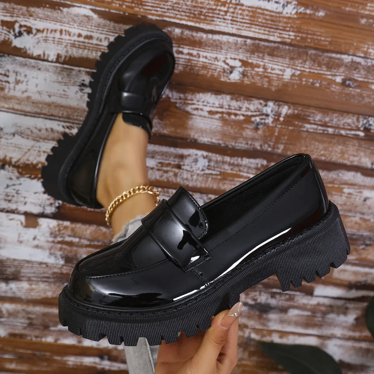 Black British style slip-on loafers with a chunky platform heel and thick rubber sole on a plain background.