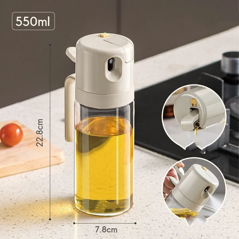 Warm grey glass oil sprayer bottle with a dual-mode cap switch, shown on a kitchen counter.