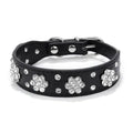 A decorative black PU leather dog collar with a sparkling rhinestone flower pattern and silver metal studs, shown adjusted with a metal D-ring.