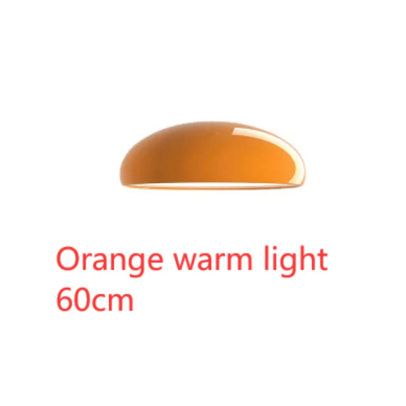 Orange iron Danish-style pendant lamp with adjustable cable above a restaurant table.