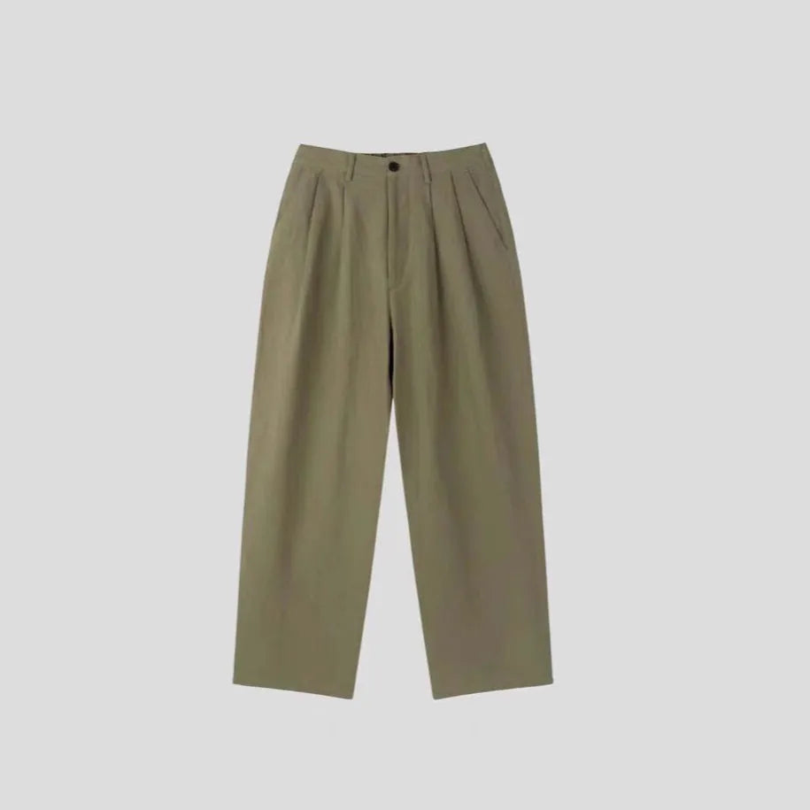 Men's apricot coloured loose-fit cotton linen suit trousers with a pencil leg on a neutral background.