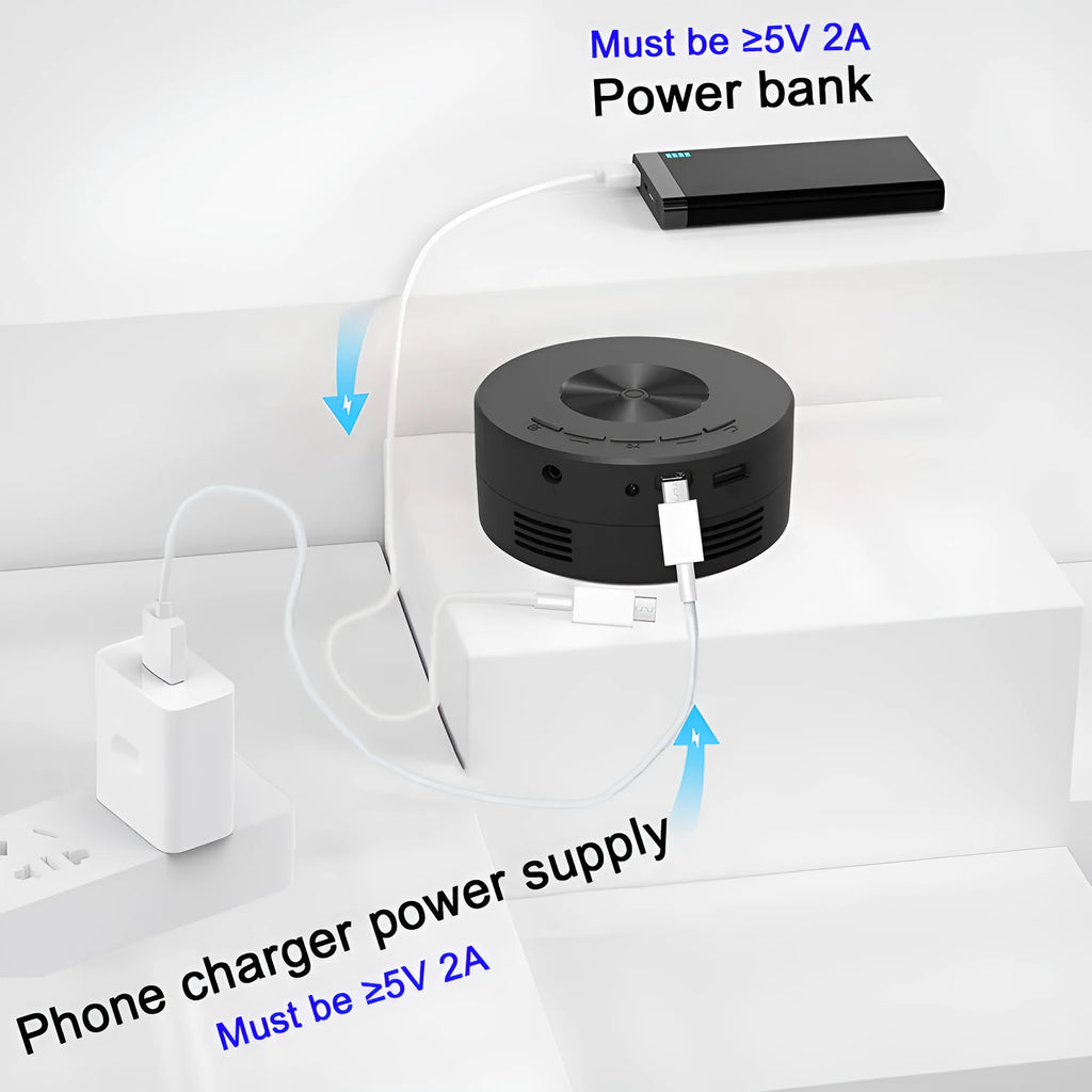 Black portable mini projector for children next to a mobile phone on a table.