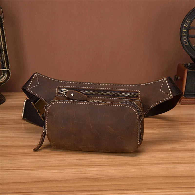 Brown top layer cowhide men's waist bag with pull-cord closure, shown open to reveal internal laptop sleeve and phone pocket.