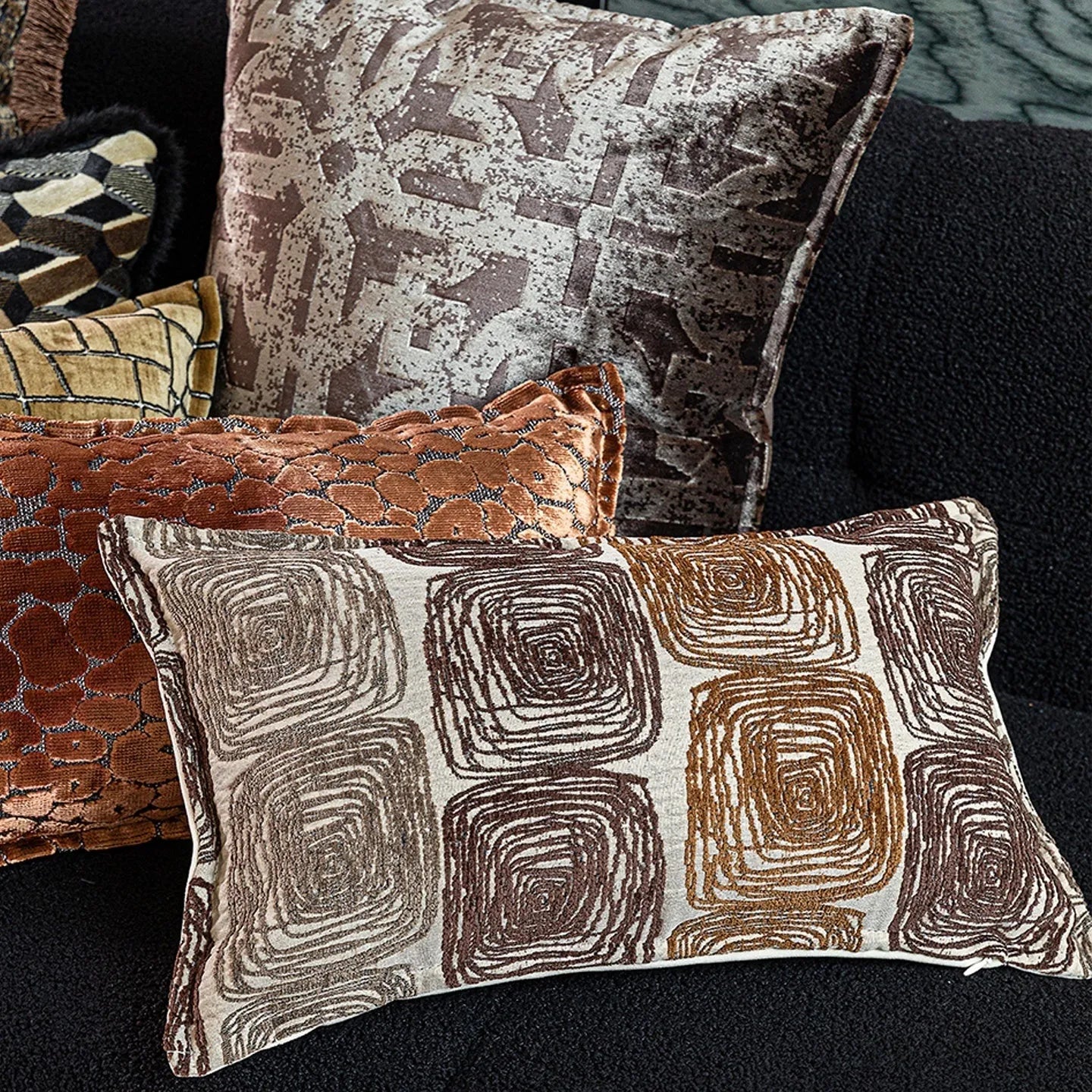 Cream and coffee abstract coil pattern square decorative pillow cover on a grey sofa.