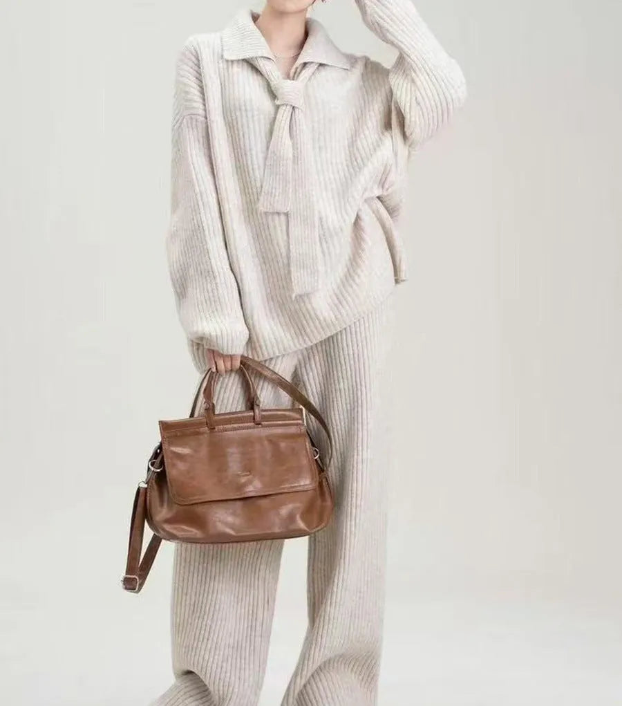 Women's beige knitted two-piece suit set showing V-neck top and straight-leg trousers on a hanger.