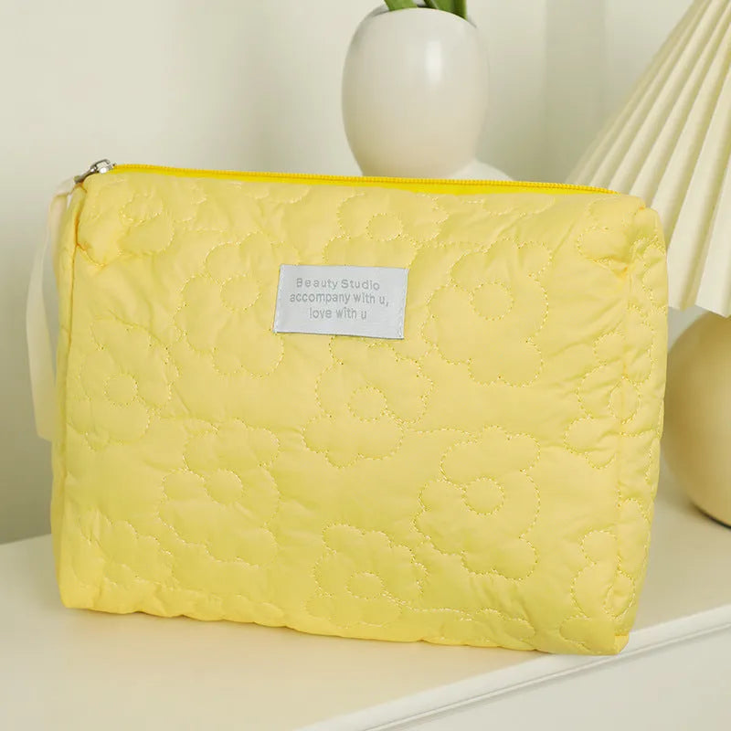 Silk quilted cosmetic storage bag for women shown in a candy colour, with a quilted pattern and zip closure.