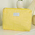 Silk quilted cosmetic storage bag for women shown in a candy colour, with a quilted pattern and zip closure.