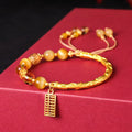 Close-up of a women's beaded bracelet with diamond-shaped tigereye and citrine stones and copper details.