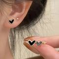 Set of three pairs of heart-shaped alloy earrings in gold, black, black and white, and pink colours