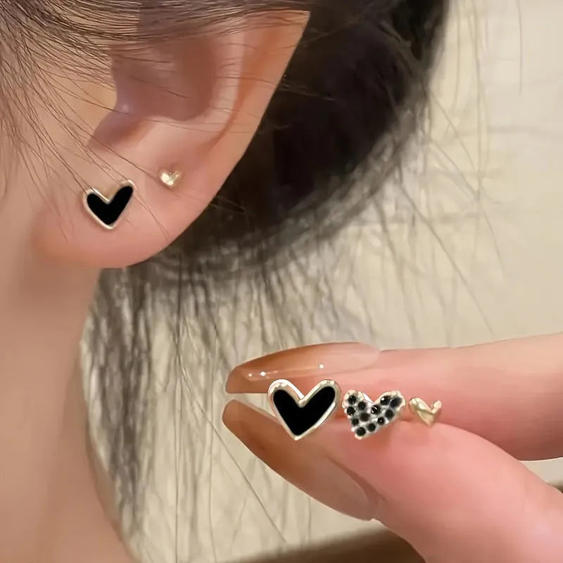 Set of three pairs of heart-shaped alloy earrings in gold, black, black and white, and pink colours