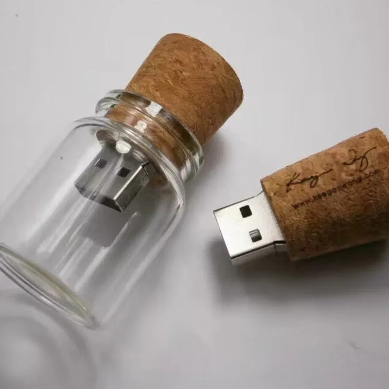 Wooden and transparent glass bottle-shaped USB flash drive on a wooden surface.