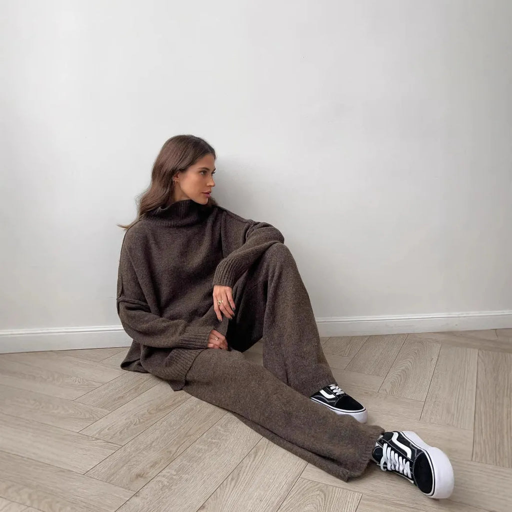 Women's dark grey acrylic knit suit with side-slit hem sweater and matching trousers laid flat.