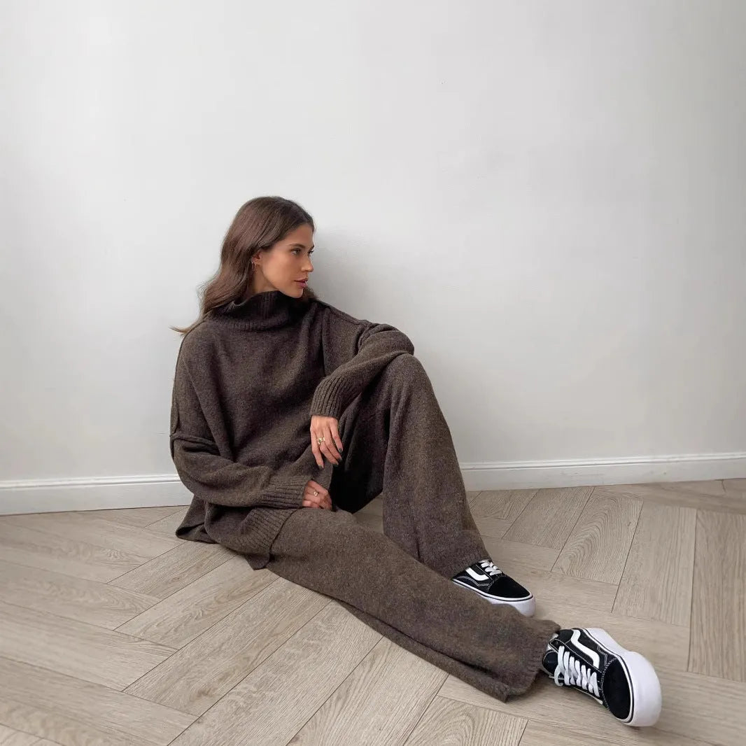 Women's dark grey acrylic knit suit with side-slit hem sweater and matching trousers laid flat.