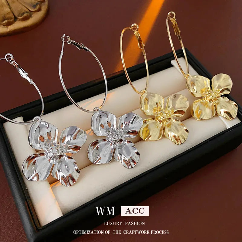 A pair of metal flower geometric earrings with a silver needle post in a gold or silver electroplated finish.