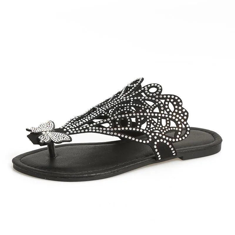 Women's black slip-on sandals with rhinestone details, a flip-toe strap, and a flat rubber sole.