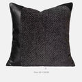 Grey and white plaid bed blanket draped over a dark grey duvet with a matching pillowcase and round leather-look cushion.