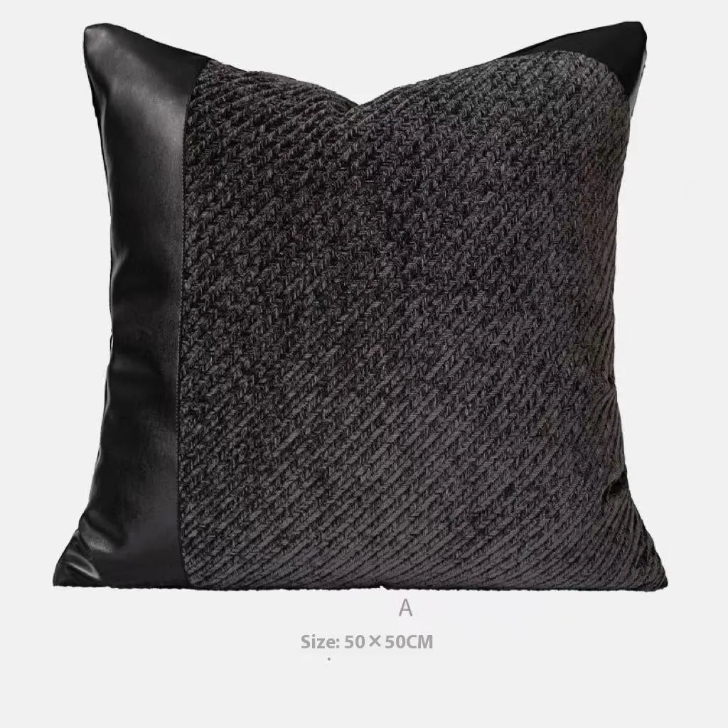 Grey and white plaid bed blanket draped over a dark grey duvet with a matching pillowcase and round leather-look cushion.
