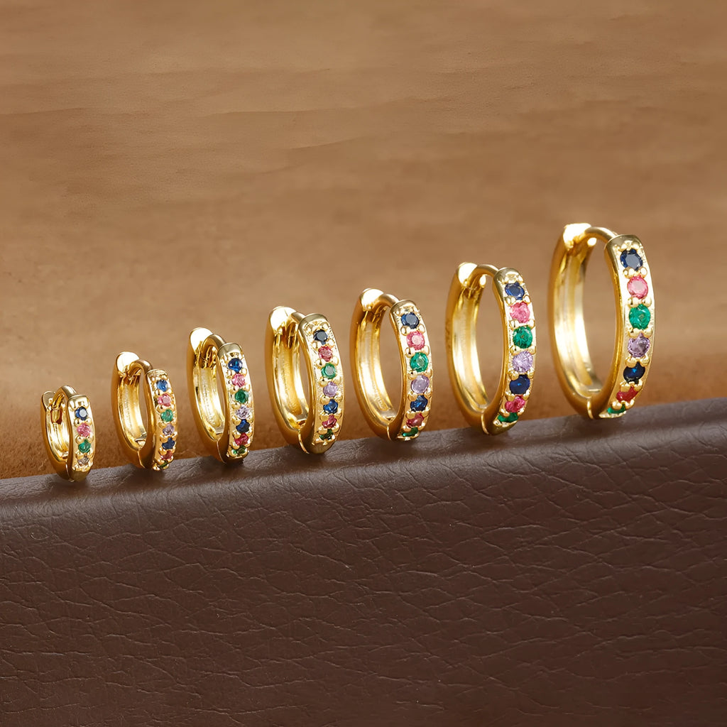 Gold, rose gold, and silver circle-shaped perforated stud earrings on a plain background.