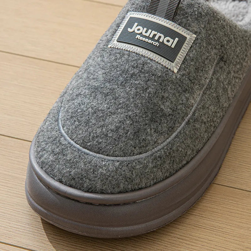 Men's grey suede slippers with a thickened sole shown on a wooden floor.
