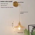 Retro brass lotus wall lamp with a 22cm green glass shade mounted on a copper base beside a bed.