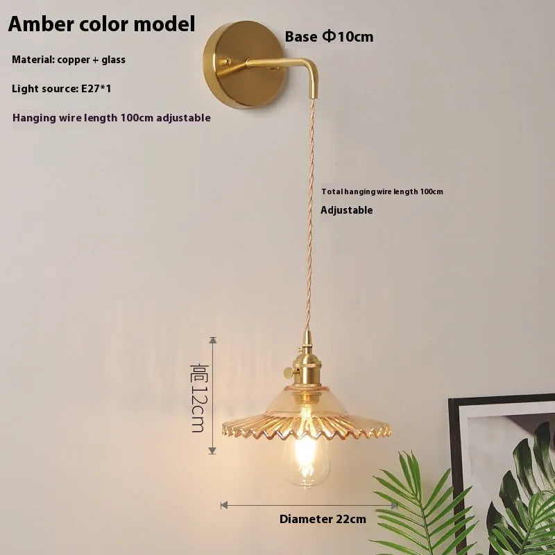 Retro brass lotus wall lamp with a 22cm green glass shade mounted on a copper base beside a bed.