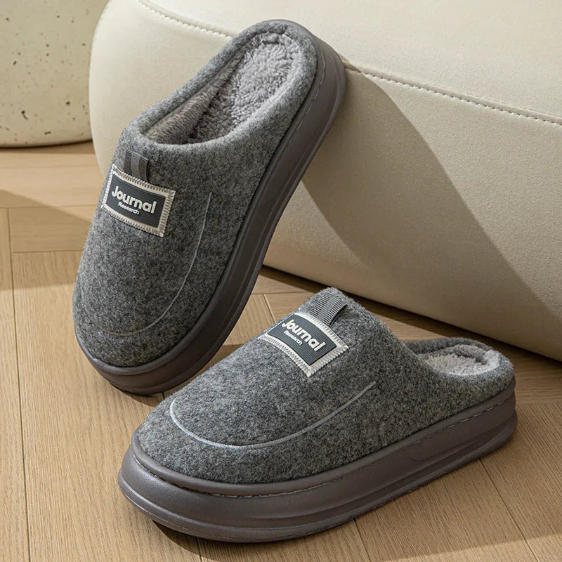 Men's grey suede slippers with a thickened sole shown on a wooden floor.