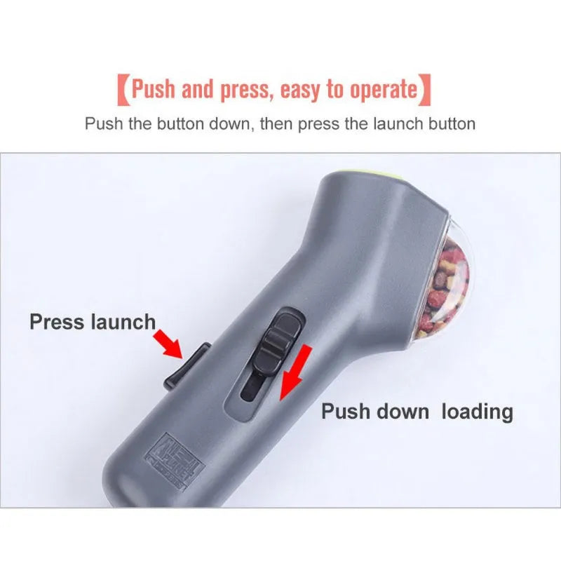 Grey pet snack catapult launcher toy on grass, showing spring trigger and treat slot.