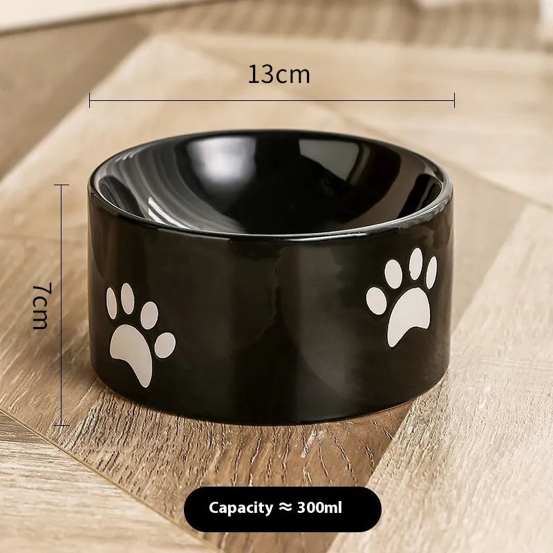 Ceramic cat food bowl with high foot base in a cat's paw print design