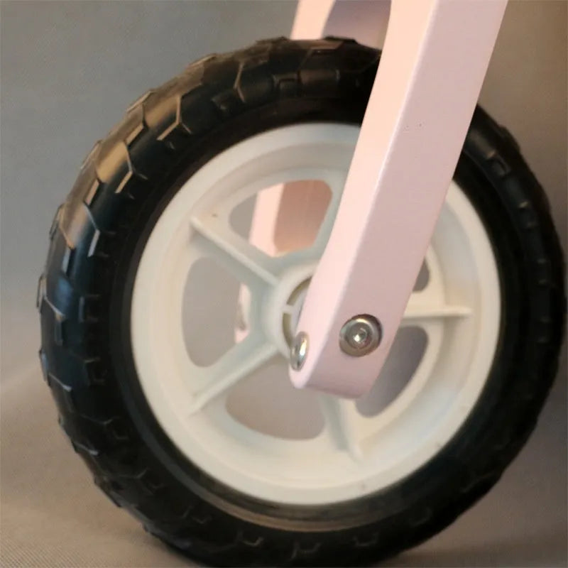 Pink wooden balance scooter for toddlers with 10-inch wheels.