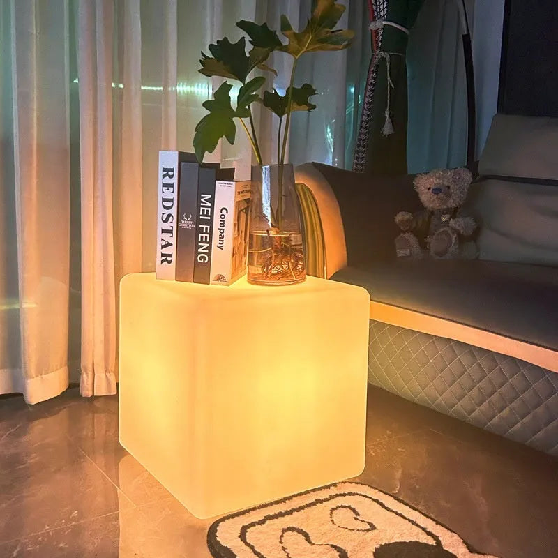 A white square cube LED stool light sitting on a patio, illustrating its modern design and outdoor use.