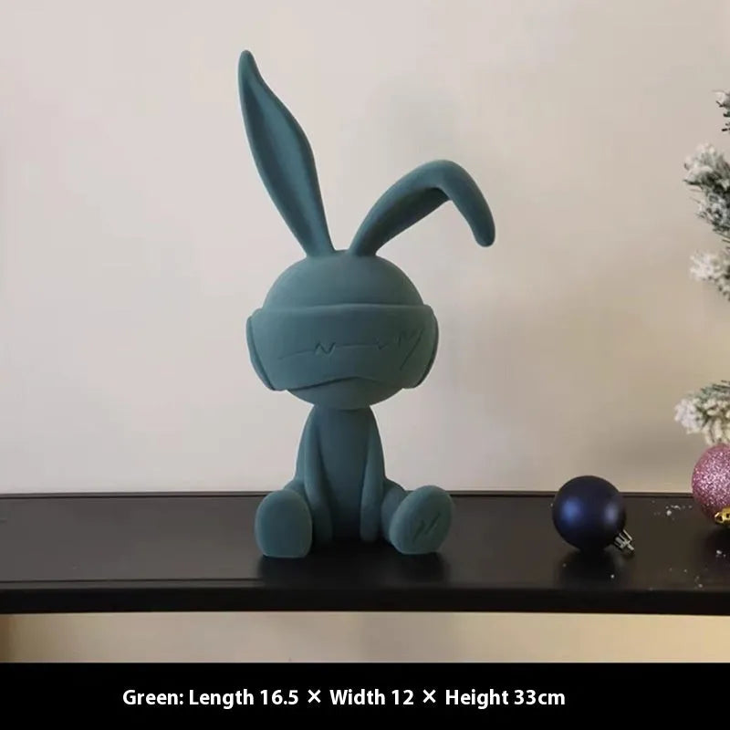 Green suede blindfold rabbit resin table ornament on a wooden surface.